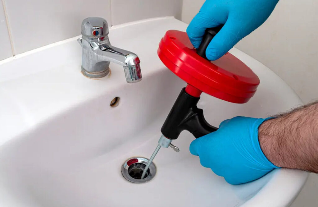 Using an auger for drain cleaning.